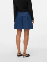 Pollera corta de denim azul medio, con tiro medio y cierre de cremallera. Presenta un diseño con un volante fruncido en el ruedo.