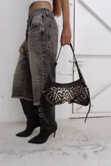 Cartera bandolera de gabardina con estampado animal print y detalles en cuero negro. Tiene correa regulable para usar al hombro, avíos metálicos plateados y cierre YKK de aluminio.