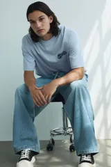 Remera de punto de algodón color celeste claro, con cuello redondo y hombros caídos. Presenta un pequeño estampado en tipografía graffiti azul oscuro en el pecho.