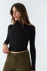 Polera color beige de corte crop, cuello alto y mangas largas.