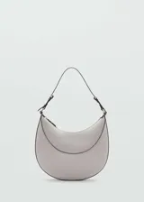 Bolso tipo hobo color gris claro con forma de media luna. Tiene asa corta ajustable, cierre superior con cremallera y forro interior.