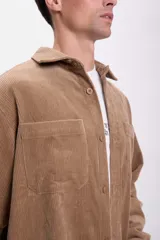 Sobrecamisa de pana color tostado, de corte recto, con cuello camisero, cierre frontal con botones, dos bolsillos de parche en el pecho y mangas largas con puños abotonados.