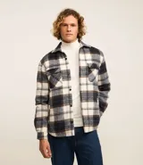 Campera trucker masculina de franela a cuadros en tonos blanco, negro y gris, con cuello inglés, abotonado delantero, bolsillos con solapa en el pecho y bolsillos laterales. Interior forrado en sherpa.