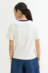 Remera blanca de algodón con cuello redondo y mangas cortas. El cuello es de color azul marino en contraste.