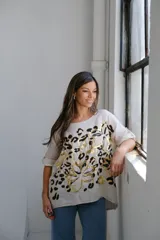 Remera beige de corte holgado con estampado de flores abstractas en dorado y negro.