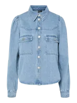 Camisa de denim celeste de algodón, de corte regular, con cuello clásico, mangas largas con puños abotonados, bolsillos con solapa abotonada en el pecho y cierre frontal con botones.