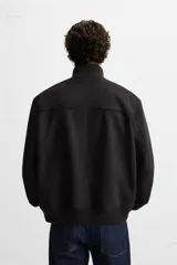 Cazadora color gris claro de corte regular, confeccionada en tejido con efecto ante. Tiene cuello alto, cierre frontal con cremallera, bolsillos laterales y puños y bajo en rib elástico.