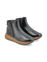 Bota corta de cuero sintético negro con cierre lateral y suela marrón.