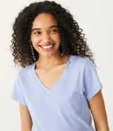 Blusa blanca de algodón con cuello en V, manga corta y bolsillo frontal.