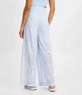 Pantalón largo de tela laise color celeste con textura de florcitas y calados. Tiene corte ancho, bolsillos laterales y cierre invisible.