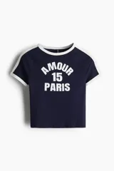Remera corta azul marino con mangas raglán blancas. Estampado frontal con la palabra "Amour", el número "15" y la palabra "Paris" en blanco.