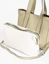 Bolso tipo shopper color beige, confeccionado en cuero vegano, con doble asa de hombro y correa extraíble regulable para usar cruzado. Incluye un bolso interno de tela con cierre.