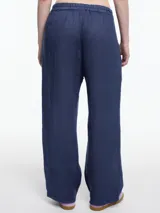 Pantalón negro de lino con elástico en la cintura y calce relajado. Incluye bolsillos laterales y un bolsillo invertido. Detalles de bordado tipo pespunte en color gris recorren la pierna y el bajo.