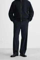 Pantalón de vestir azul marino, de corte recto, con bolsillos laterales y traseros. Incluye un bolsillo tipo cargo en la pierna izquierda. Se ajusta a la cintura con cinturón de cuero marrón.
