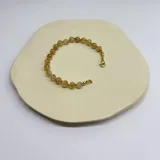 Pulsera elástica con cuentas de citrino de 6 mm de diámetro y separadores de hilo beige. Terminaciones en acero hipoalergénico con baño dorado.