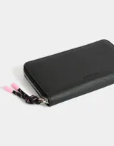 Billetera negra de cuerina con cierre y puller del mismo material. Tiene tag en relieve y monedero interno con cierre.