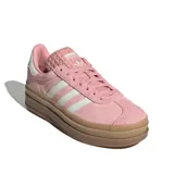 Championes Adidas modelo Gazelle Bold W, color rosa claro con tres franjas blancas en el lateral. Presentan una plataforma gruesa de goma color goma/marrón claro. El talón es blanco y la lengüeta tiene un patrón texturizado.