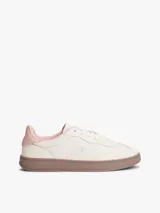 Zapatillas deportivas de corte bajo confeccionadas en piel napa de color beige claro. Presentan un diseño clásico con cordones al tono, un monograma TH texturizado en el lateral y un panel de contraste en el talón de color rosa. La suela es de goma en tono marrón claro.