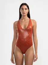 Malla entera color ladrillo con estampado de piel de serpiente, escote en V y espalda descubierta con tiras cruzadas unidas por un detalle metálico cuadrado.