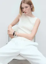 Top blanco sin mangas, con cuello barco, diseño entallado y detalle de costura en la parte delantera.