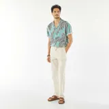 Camisa celeste con estampado de hojas de palmera en tonos negro y blanco, de corte recto, con cuello cubano y mangas cortas con dobladillo.