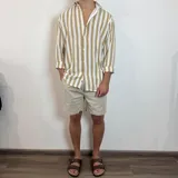 Camisa de lino a rayas verticales color beige y blanco, de corte holgado y manga larga con puños abotonados.