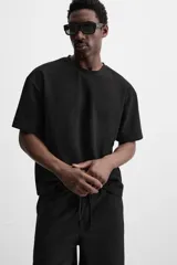 Camiseta negra de corte holgado, con cuello redondo y mangas cortas.