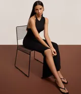 Vestido largo negro de microfibra, corte ajustado al cuerpo, con cuello redondo y escote tipo nadador en la espalda. Presenta una abertura lateral alta en la falda.