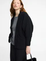 Cardigan negro de punto, con diseño holgado y bolsillos frontales.
