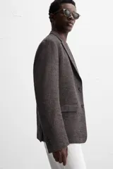 Blazer marrón con estampado pata de gallo, de corte regular fit, con cuello de solapas de muesca, manga larga con puños abotonados, bolsillo de vivo en el pecho, bolsillos de solapa en la cadera, bolsillo interior, aberturas en la espalda y cierre frontal con botones.