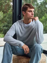 Sweater de punto gris claro jaspeado, de manga larga y cuello redondo. Corte ajustado.