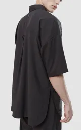 Camisa negra de manga corta con doble bolsillo ojal en delantero, realizada en tejido plano y silueta oversize.