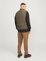 Chaleco acolchado verde militar sin mangas, con cuello alto, cierre frontal con cremallera y bolsillos delanteros.