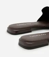 Sandalia plana de mujer color blanco hueso, con tira única ancha y puntera cuadrada abierta. Posee un taco bajo y suela de goma marrón.