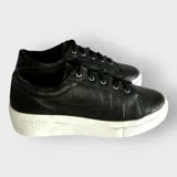 Zapatillas urbanas negras con textura de cocodrilo, cordones negros y suela de goma blanca.