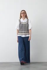 Top tejido sin mangas con diseño geométrico de rombos en relieve, en tonos azul marino y beige. Presenta escote amplio y breteles tejidos.