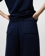 Pantalón jogger de punto color azul marino, de corte relajado y tiro alto, con pliegues frontales y puños ajustados en el tobillo.