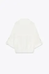 Camisa blanca de manga corta con cuello solapa, bolsillos frontales con tapeta, bajo con elástico y cierre frontal con botones a presión.