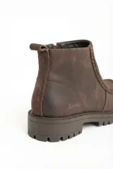 Bota de cuero color marrón con diseño que combina texturas de cuero liso y gamuza. Cuenta con suela de goma tipo track, cierre lateral para facilitar el calce y tirador trasero.