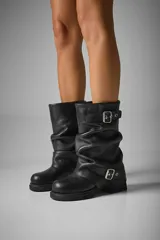 Botas de caña media color negro, confeccionadas en cuero vegano, con hebillas metálicas y suela track.