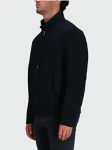 Chaqueta tipo bomber o Harrington de color azul oscuro, con cuello alto abotonado, cierre frontal de cremallera y pequeño logo bordado en el pecho.
