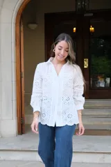 Camisa blanca de manga larga con cuello camisero y cierre frontal con botones. Detalle de bordados perforados combinados a tono.