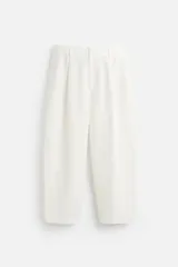 Pantalón blanco de corte relajado con pliegues frontales, bolsillos laterales y bolsillos traseros de vivo. Cierre frontal con cremallera y botón.