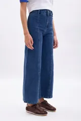 Pantalón de jean azul oscuro, corte ancho (wide leg), con costura frontal marcada en ambas piernas.