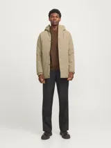 Parka larga color beige con capucha ajustable, cierre frontal con solapa cortaviento, bolsillos funcionales y puños de canalé.