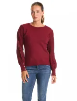 Buzo de tejido lurex marca Nanette en color bordó, con cuello a la base y mangas largas de diseño plisado. Los puños cuentan con apliques de botones decorativos.