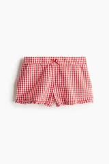 Short de algodón con estampado de cuadros vichy rojos y blancos, cintura elástica con moña de satén y ribete de volados en el bajo.
