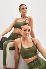 Top deportivo color beige con banda inferior azul y tirantes finos azul marino. Espalda cruzada con doble tira.