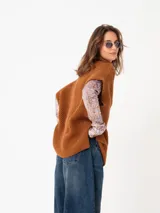 Poncho de tejido grueso color beige, con cuello alto y mangas cortas.