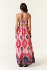 Vestido largo strapless con estampado geométrico en tonos rosados, fucsias, morados y negros. Tiene lazo para atar alrededor del cuello y detalle retorcido en el frente y en la espalda.